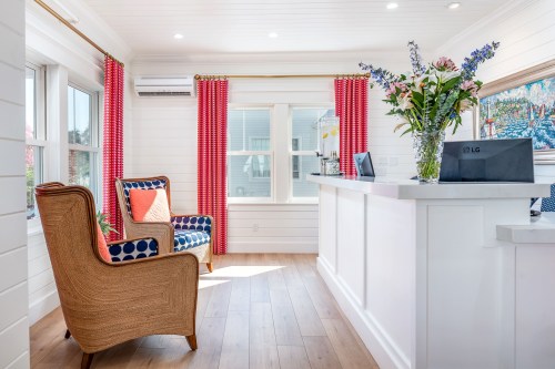 Bright reception area with a cozy chair, colorful curtains, and a flower arrangement on the front desk.