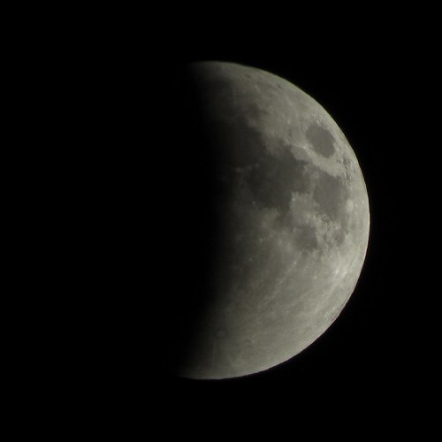 A close-up view of a partially illuminated moon against a dark sky.
