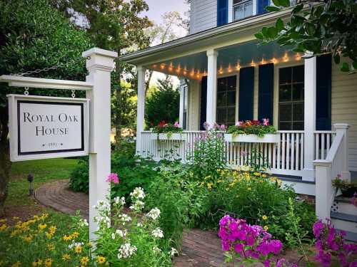 Charming house with a sign reading "Royal Oak House," surrounded by colorful flowers and greenery.