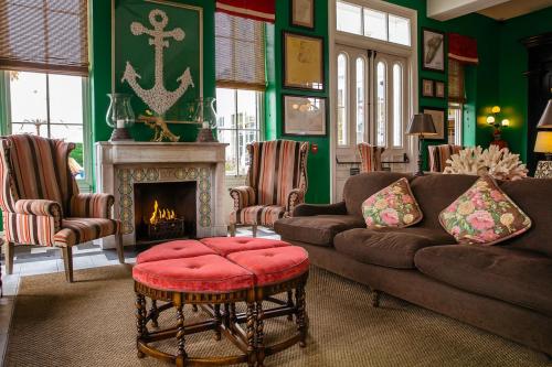 Cozy living room with green walls, striped chairs, a fireplace, and a pink ottoman, decorated with nautical themes.