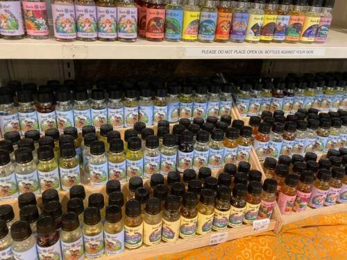 A display of various small bottles of oils arranged on shelves, featuring colorful labels and a warning sign above.