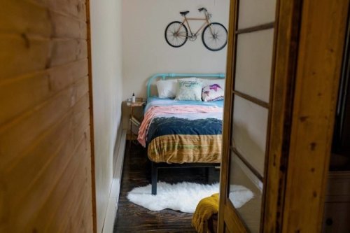 Cozy bedroom with a bike on the wall, a bed with colorful bedding, and wooden accents.