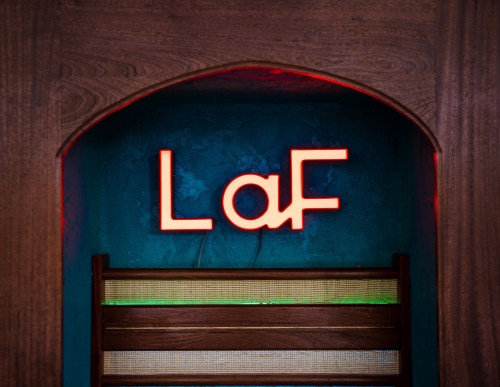 Neon sign reading "LaF" in a wooden archway against a blue wall.