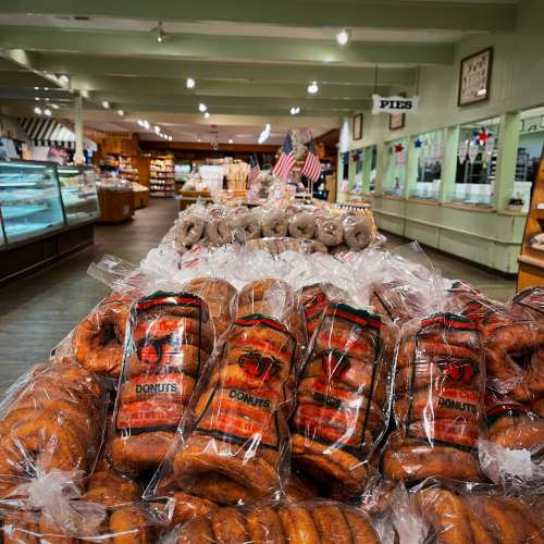 A display of packaged donuts in a shop, with shelves and American flags in the background.