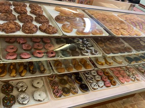 A display case filled with various donuts and pastries, including glazed, chocolate, and colorful frosted options.