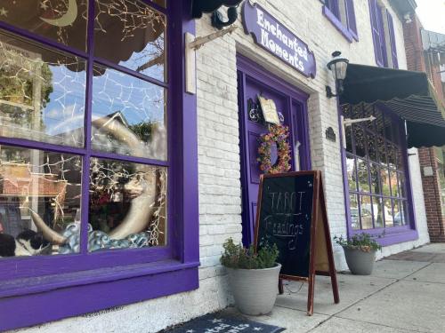 A purple storefront with "Enchanted Moments" sign, featuring a tarot readings sign and decorative windows.