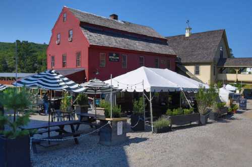 A red building with a sign, surrounded by outdoor seating and tents, set against a clear blue sky.