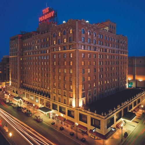 The Peabody Hotel illuminated at night, showcasing its historic brick architecture and bustling street below.