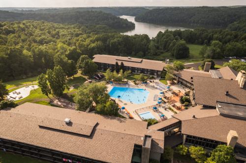 Aerial view of a resort with a pool, surrounded by greenery and a river in the background.