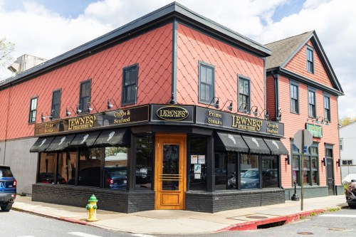 Exterior view of Lewne's, a restaurant featuring a red and black building with large windows and outdoor seating.