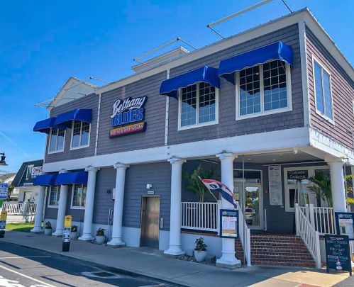 Exterior of a two-story restaurant with blue awnings, a sign reading "Bethany Blues," and a welcoming entrance.