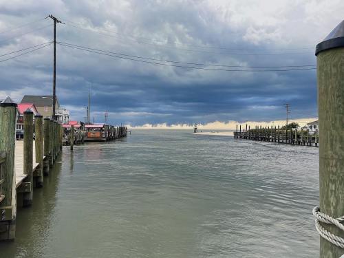 A calm waterway lined with wooden docks under a cloudy sky, leading to the horizon.