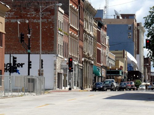 A street view featuring historic buildings, traffic lights, and parked cars in an urban setting.