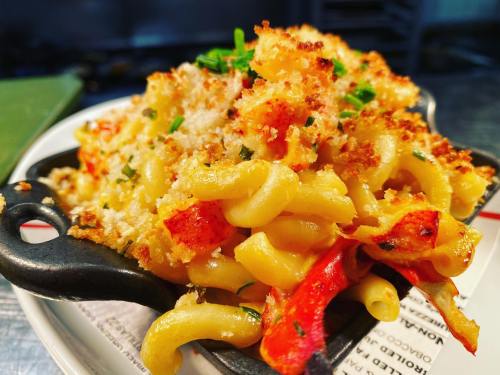 A close-up of creamy macaroni and cheese topped with breadcrumbs and red peppers, served in a small cast-iron skillet.