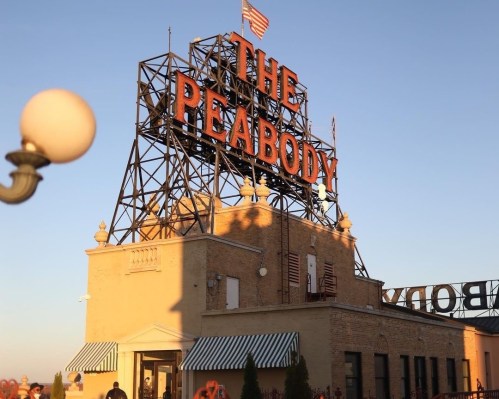 The Peabody Hotel sign atop a historic building, with a clear blue sky in the background.