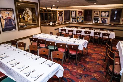 A dining area with neatly set tables and sports jerseys displayed on the walls.