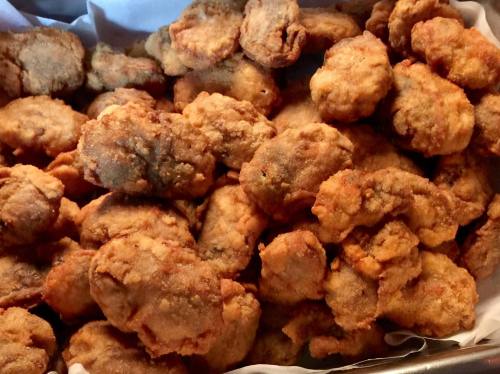 A close-up of a tray filled with golden-brown, crispy fried chicken pieces.