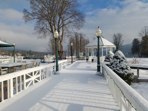 Snow-covered walkway leading to a gazebo, surrounded by trees and a serene winter landscape.