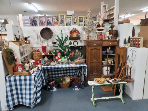 A cozy display of vintage items, including holiday decorations, wooden furniture, and various collectibles on checkered tablecloths.