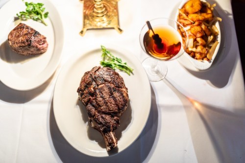 A beautifully plated meal featuring a grilled ribeye steak, a smaller cut, and a side of roasted potatoes.