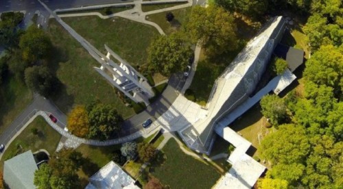 Aerial view of a modern architectural structure surrounded by greenery and pathways.