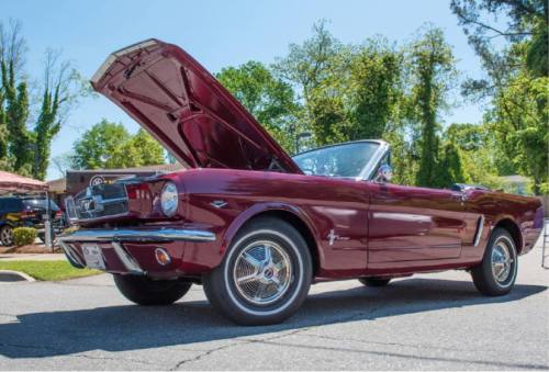 A classic maroon convertible car with the hood open, parked outdoors on a sunny day.
