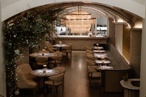 Elegant restaurant interior with soft lighting, plush seating, and a large chandelier, creating a cozy atmosphere.
