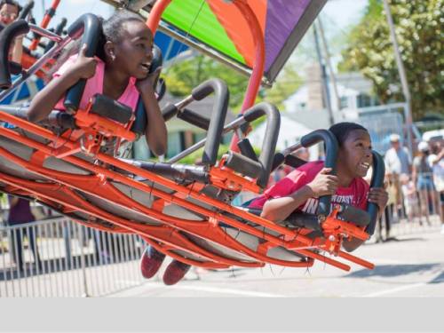 Two children enjoy a thrilling ride at an amusement park, smiling as they soar through the air.