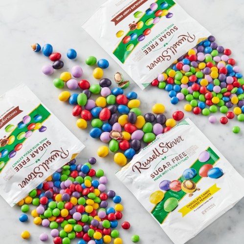Colorful sugar-free candies scattered around two open bags on a white surface.