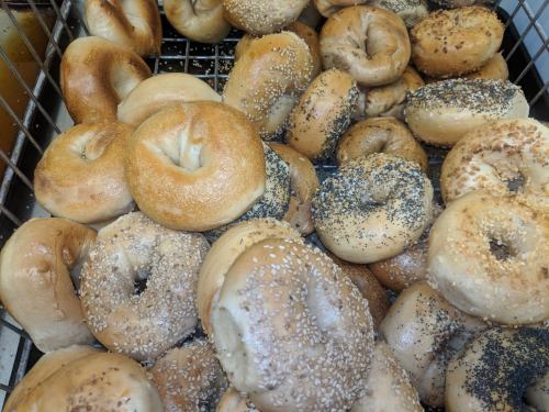 A basket filled with various bagels, including plain, sesame, and poppy seed varieties.