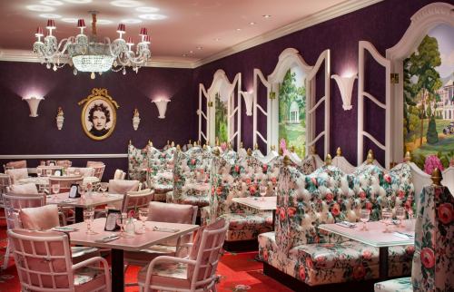 Elegant restaurant interior with floral booths, chandeliers, and decorative wall art in a vibrant color scheme.