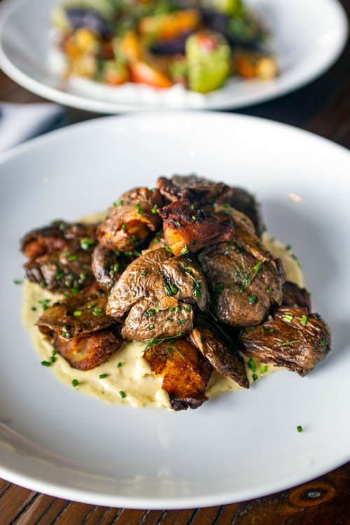 A plate of tender, sautéed meat served over creamy mashed potatoes, garnished with herbs.