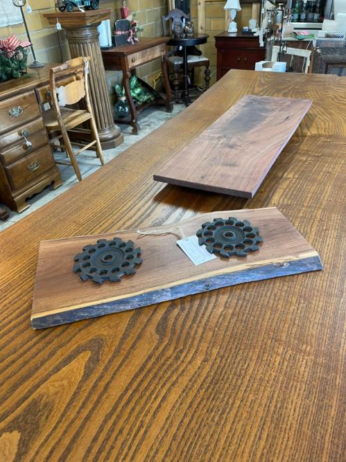 A wooden table with a long, smooth plank and two decorative metal gears on a smaller wooden piece.