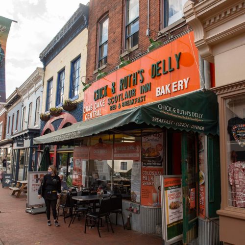 A colorful storefront of Chick & Ruth's Delly, featuring a sign for breakfast, lunch, and dinner in a charming street setting.