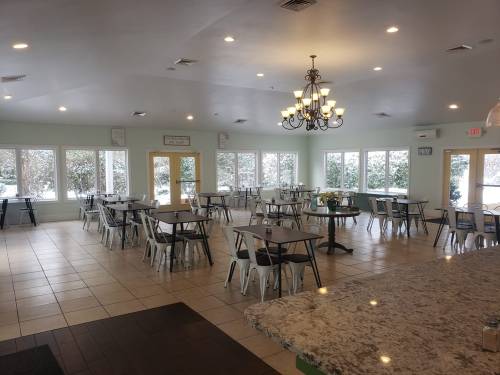 Bright, spacious dining area with tables and chairs, large windows, and a chandelier, overlooking a snowy landscape.