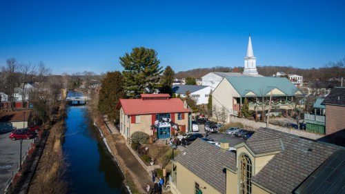 A scenic view of a canal lined with buildings and a church steeple under a clear blue sky.