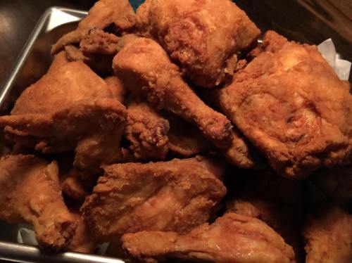 A close-up of a pile of crispy, golden-brown fried chicken pieces on a tray.