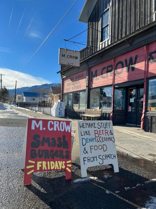 A storefront with a sign advertising "Smash Burgers Fridays" and another promoting handmade goods like beer and food.
