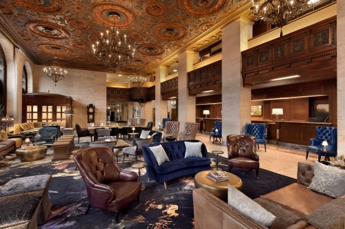 Luxurious hotel lobby featuring ornate ceiling, elegant seating, and warm lighting. Cozy and inviting atmosphere.