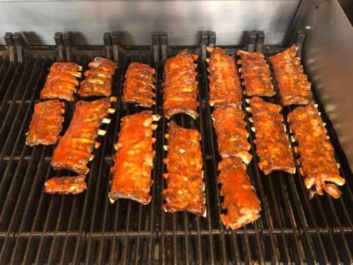 Grilled ribs coated in barbecue sauce, arranged on a barbecue grill.