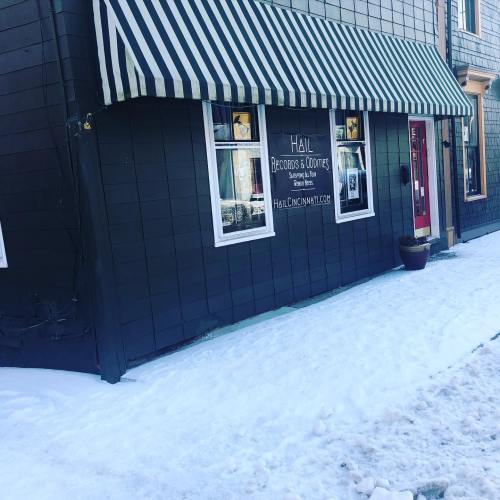 A black building with a striped awning, snow on the ground, and a sign for "Hail Records & Clothing."
