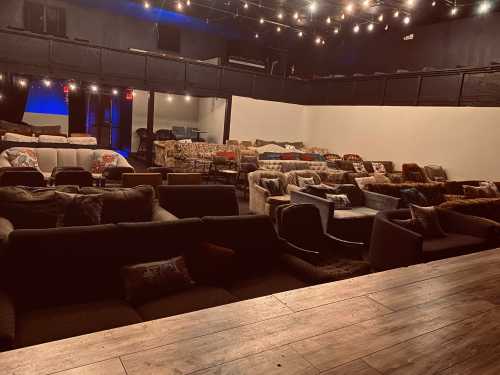 A cozy venue with multiple couches arranged for seating, dimly lit with string lights overhead.