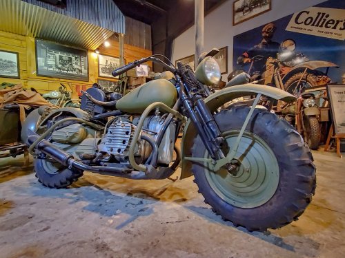 A vintage military motorcycle displayed in a museum, featuring a rugged design and large tires.