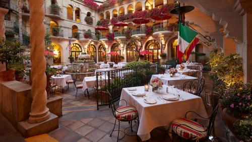 Charming outdoor restaurant with tables, vibrant flowers, and Italian flag, set in a beautiful courtyard.