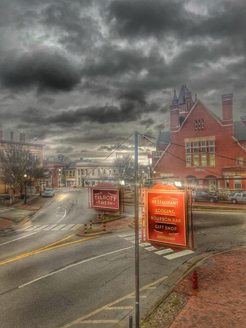 A street view featuring the Talbott Tavern sign, with a cloudy sky and historic buildings in the background.