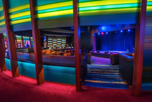 A vibrant performance venue with colorful lighting, empty seating, and a stage ready for a show.