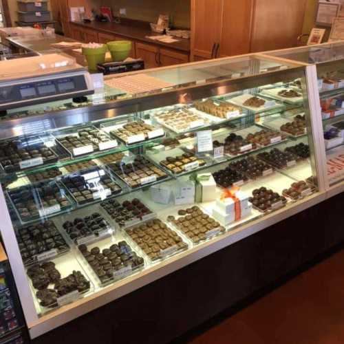 A display case filled with various chocolates and confections in a cozy shop setting.