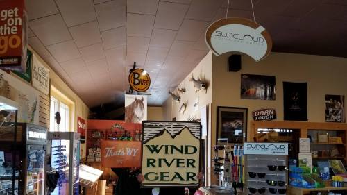 Interior of a store featuring various signs, including "Wind River Gear" and "Sundial Club," with merchandise displays.