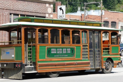 A vintage-style trolley bus with green and wood accents parked on a street, with a "right turn only" sign above.