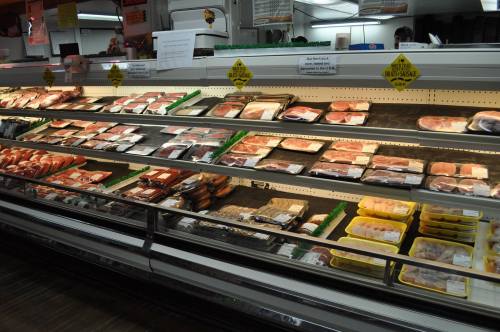A well-stocked meat display case featuring various packaged meats and poultry in a grocery store.